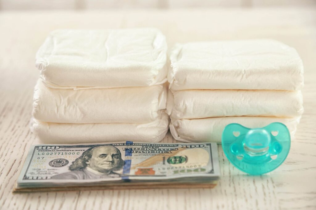 Parenting expenses concept. Pile of diapers, pacifier and money