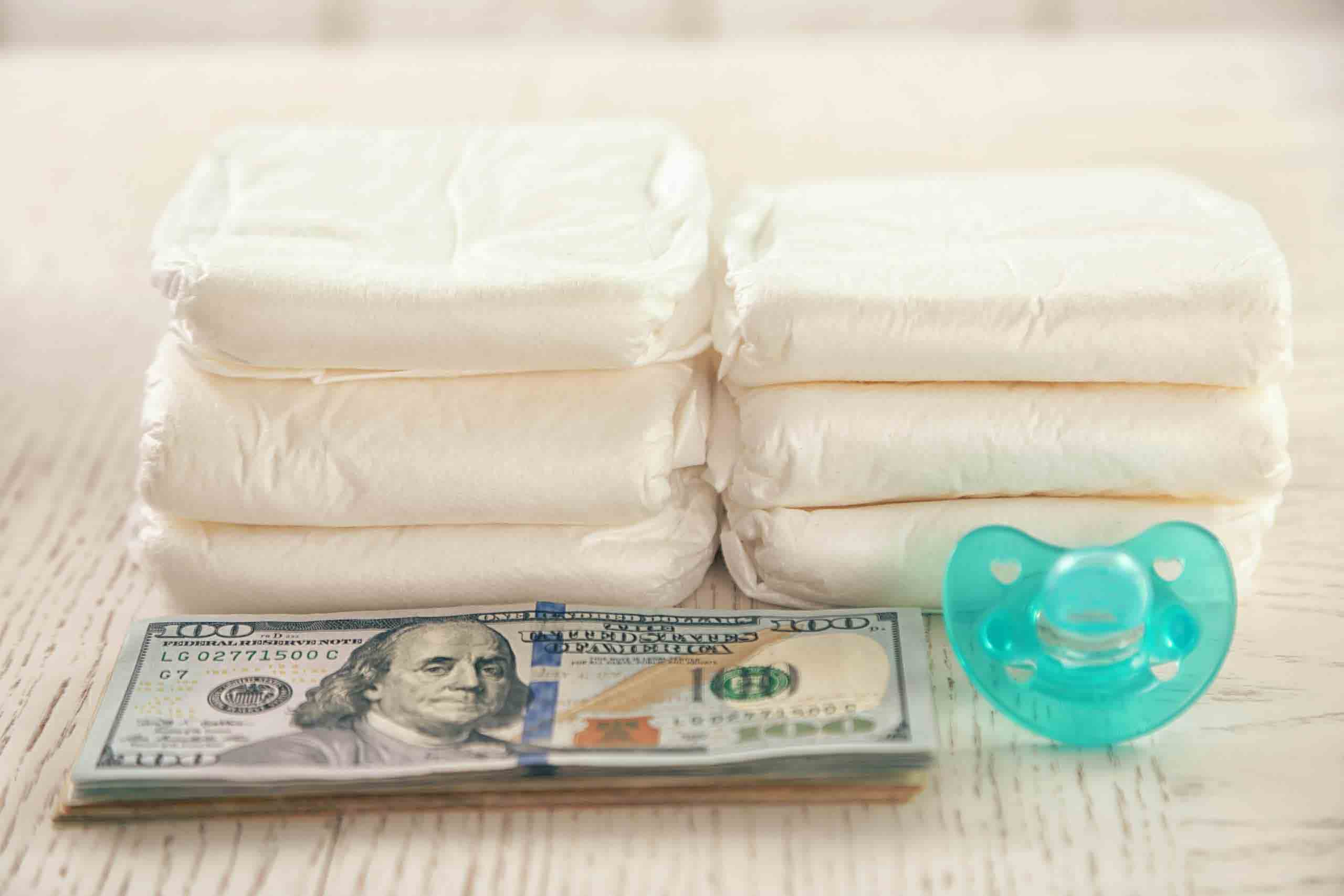 Parenting expenses concept. Pile of diapers, pacifier and money