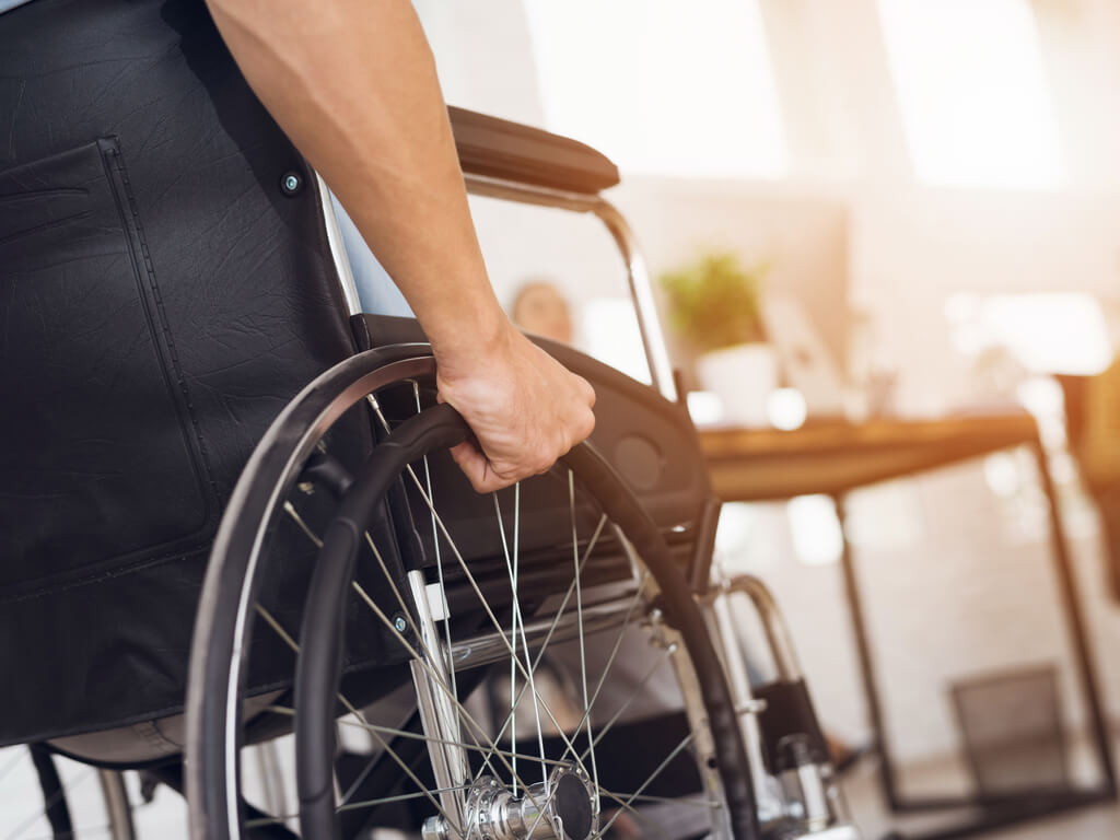 man with a disability sitting in a wheelchair with his hand on the wheel