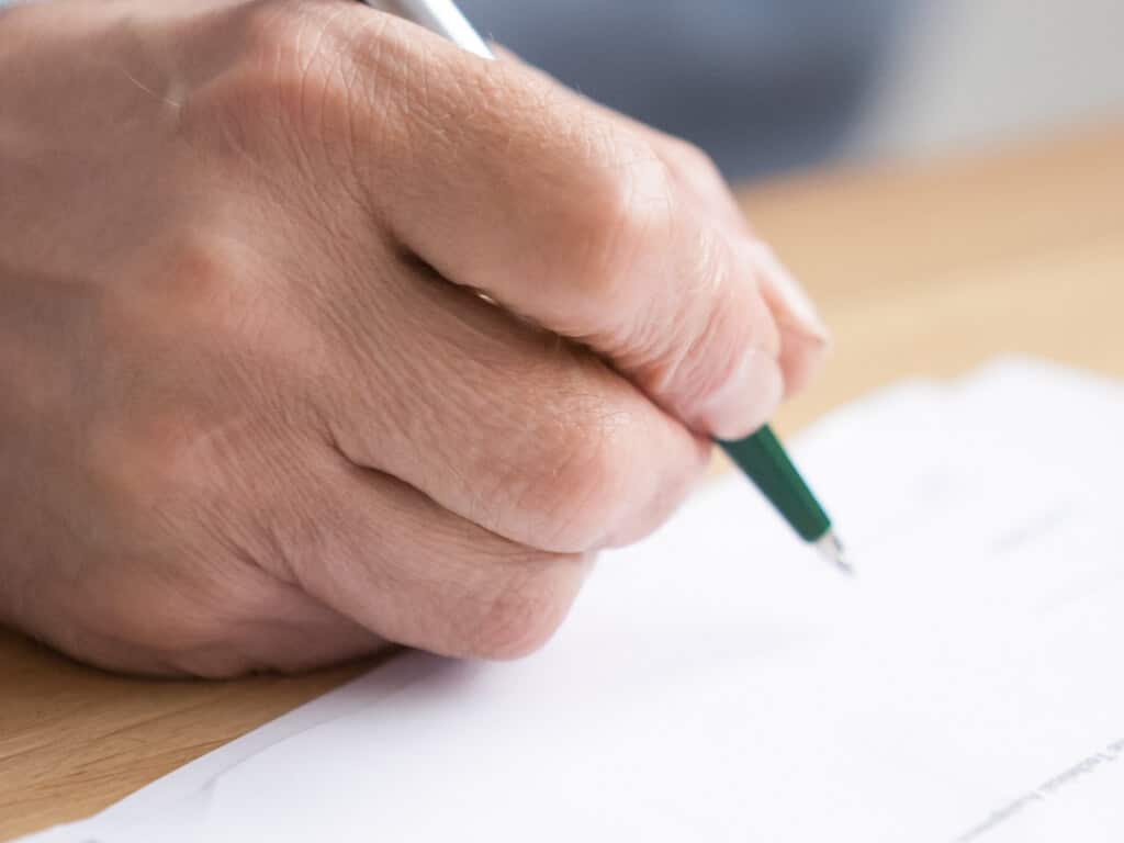 elderly hand signing legal documents
