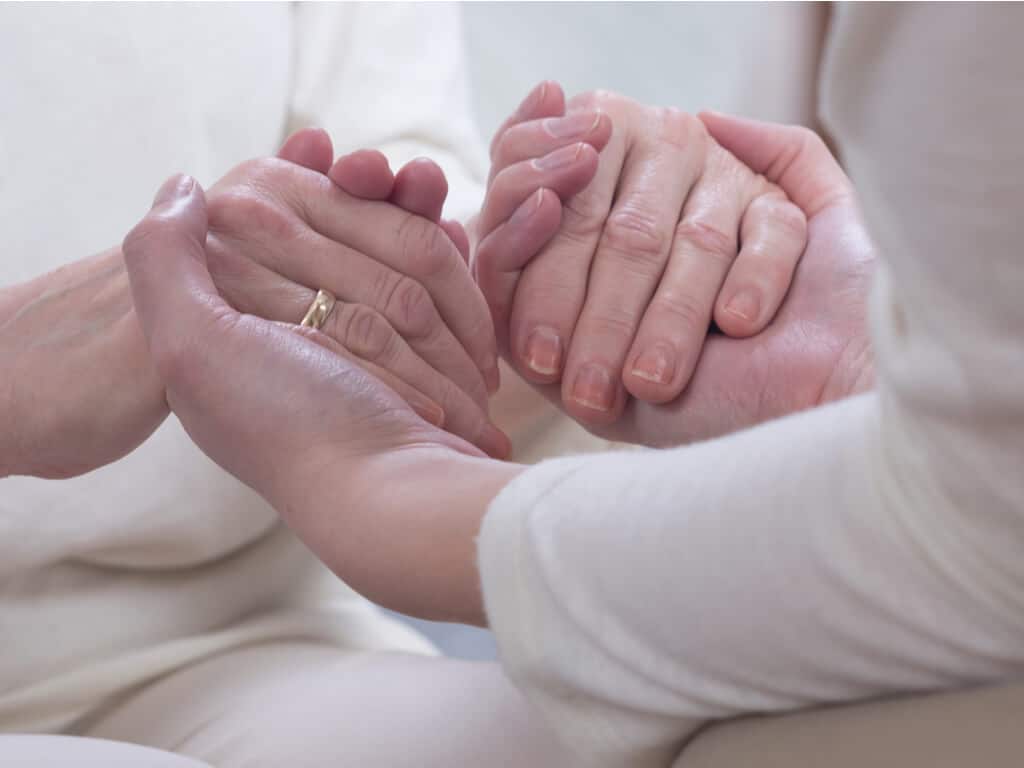 two elderly individuals holding hands