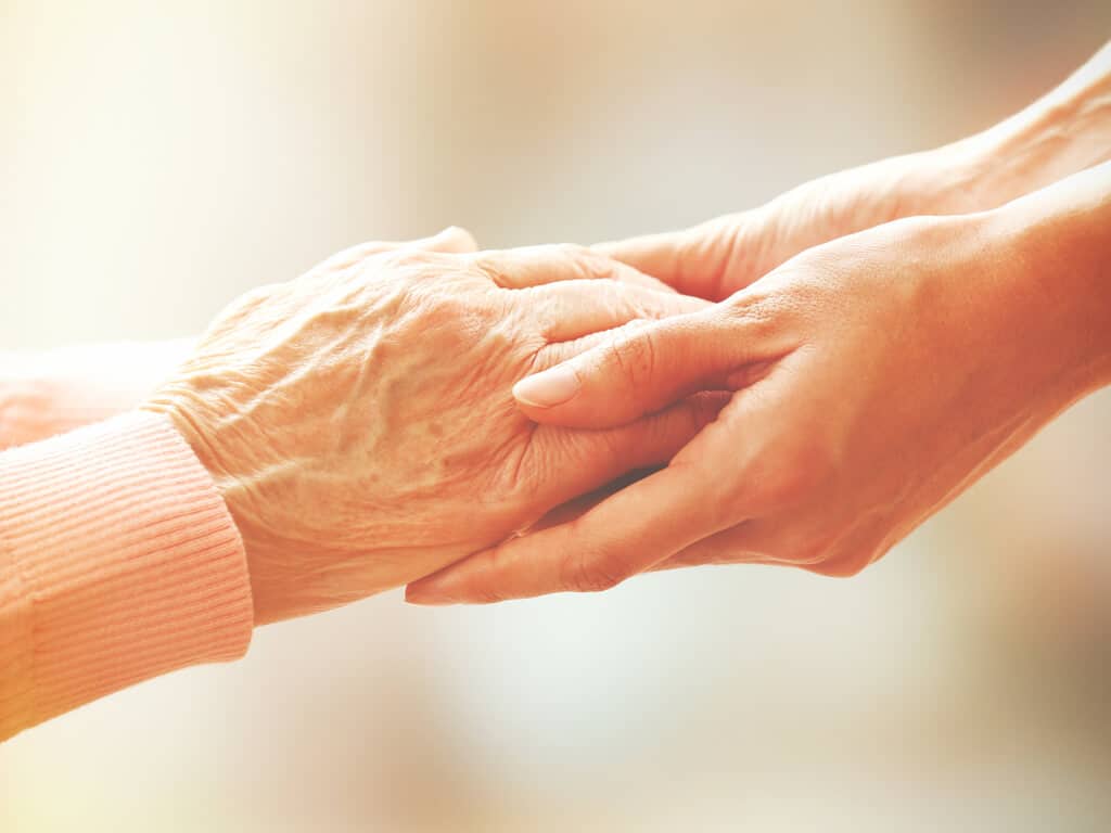 young hands holding elderly hands