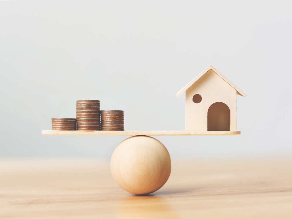 money and a wooden home balancing