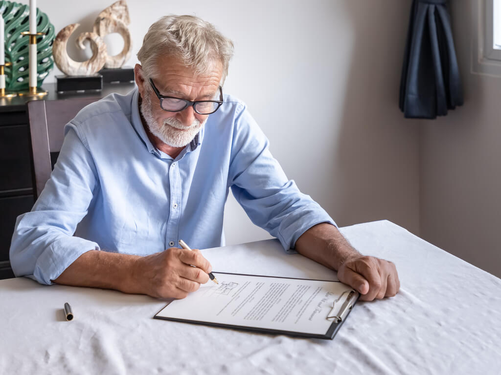 An elderly man signing an important paper