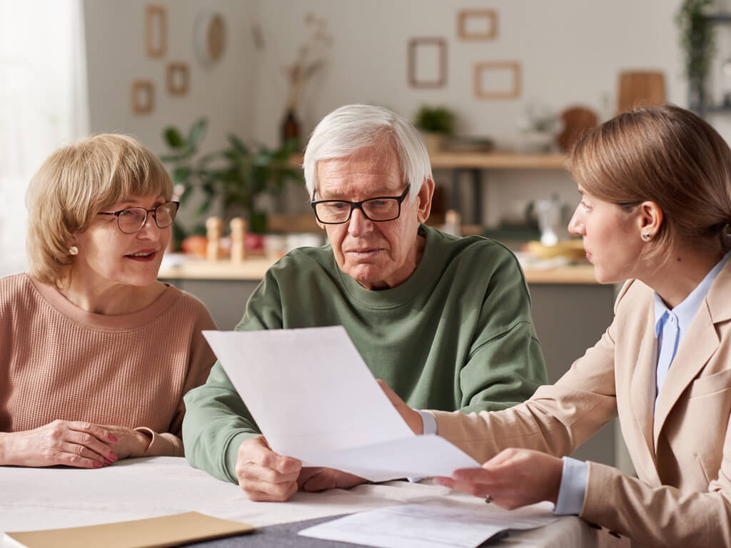 an elderly couple reviewing document with a woman