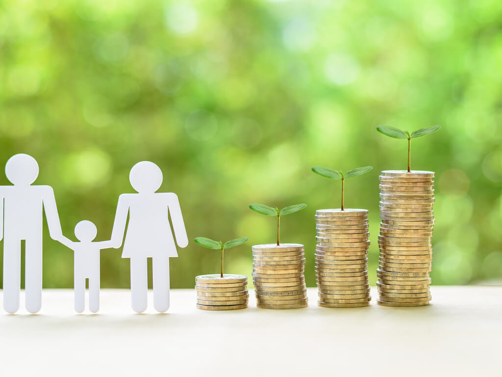 a cutout family on a table standing next to stacks of coins