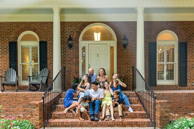 Blended family on stairs of estate